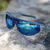 blue popticals sunglasses sitting on a rock 