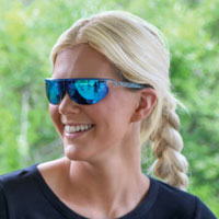 woman smiling looking off to the side wearing popticals sunglasses 